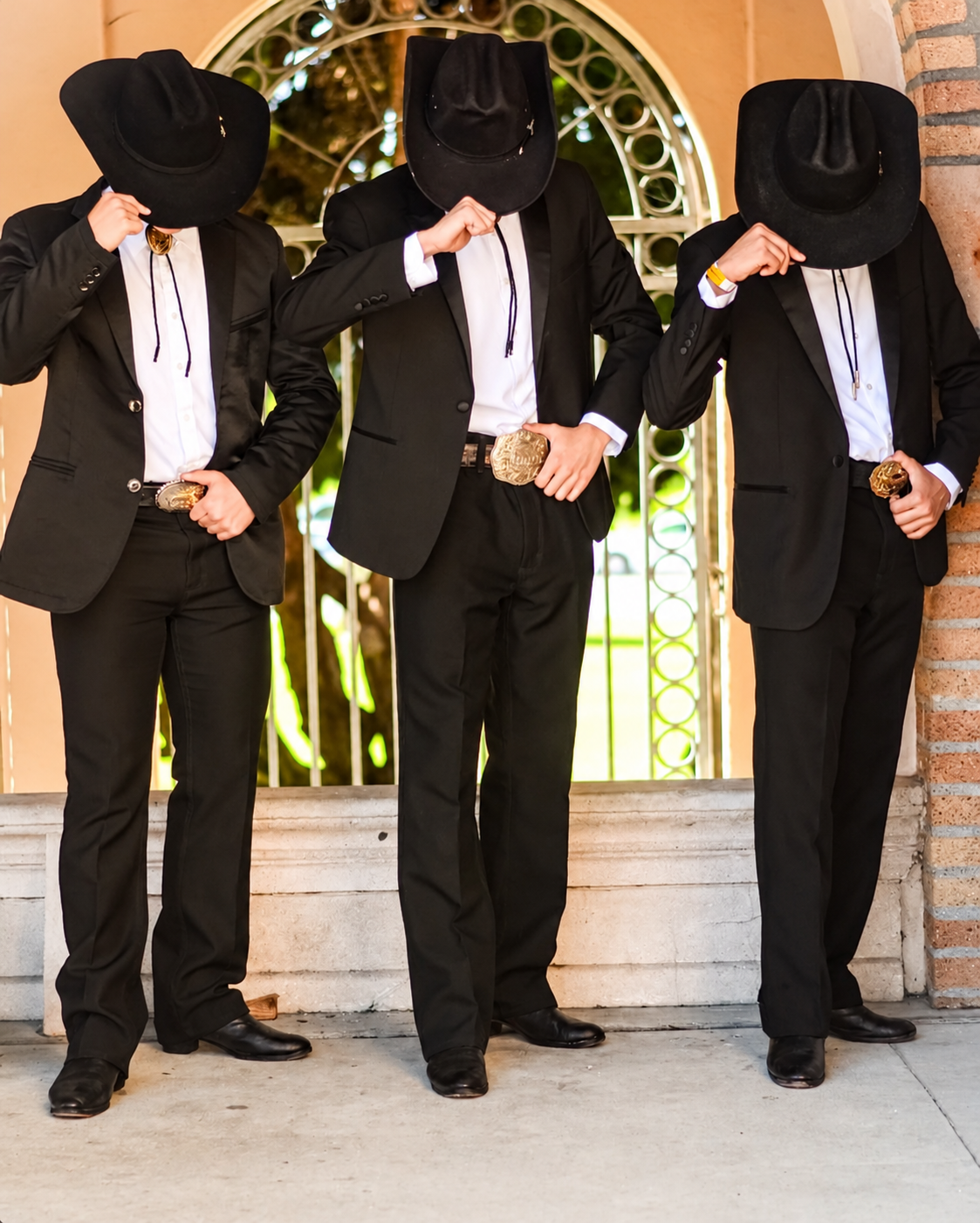 Tres bailarines con trajes negros y sombreros inclinados